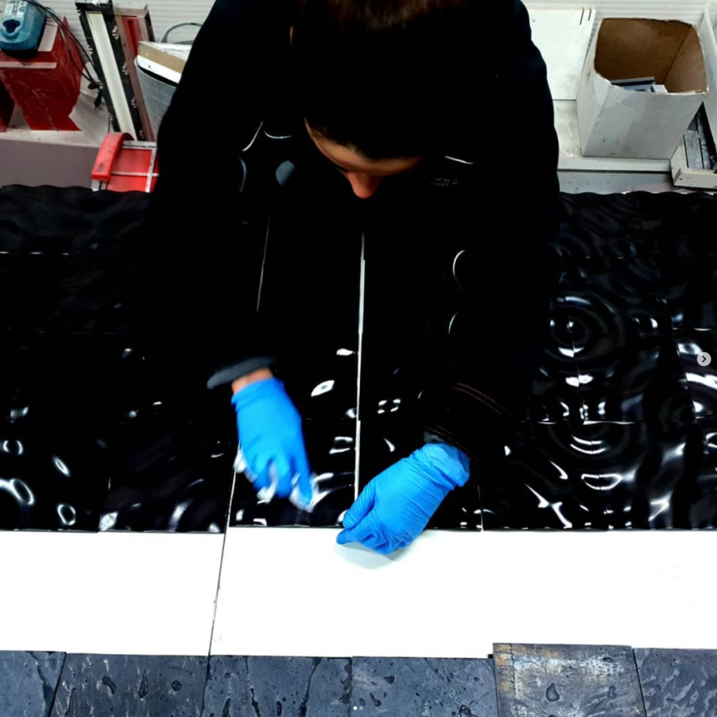 Handcrafted concrete tiles being polished in a production facility, highlighting artisanal techniques by Musca Studio